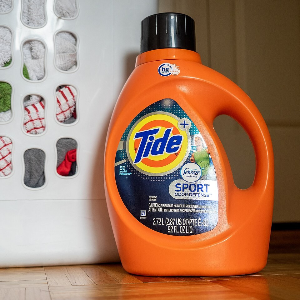 Оранжевая бутылка жидкого стирального средства Tide на столе.